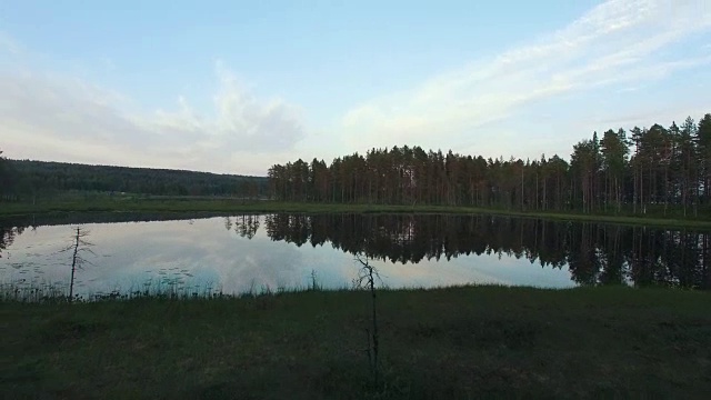 从森林上空飞过平静湖面的航拍照片。瑞典北部美丽的风景视频素材