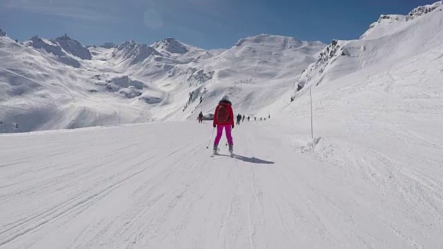 运动中的后视图滑雪者在山上度假胜地滑雪坡上滑雪视频素材