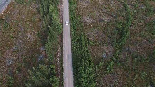 汽车在乡村道路上行驶的鸟瞰图。无人机飞过森林的砾石路视频素材