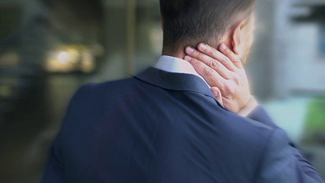 西装男遭受颈部疼痛，被动的生活方式导致脊柱问题视频素材