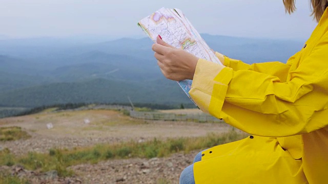 年轻女性徒步旅行者从山顶看地图视频素材