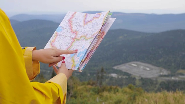 年轻女性徒步旅行者从山顶看地图视频素材