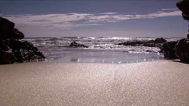 阳光反射的沙子和海浪击中海滩视频素材