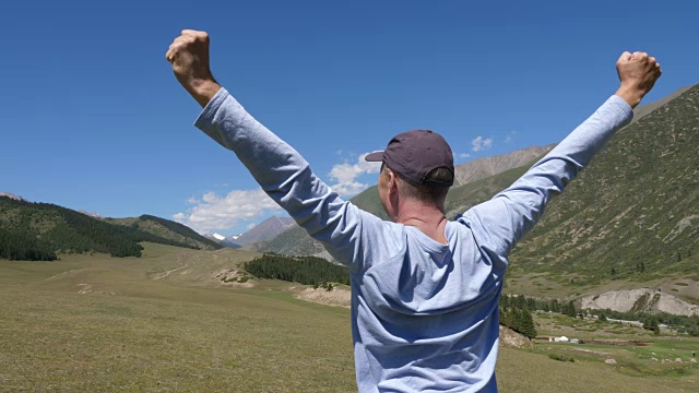 旅行者举起双手庆祝绿色山谷的成功视频素材