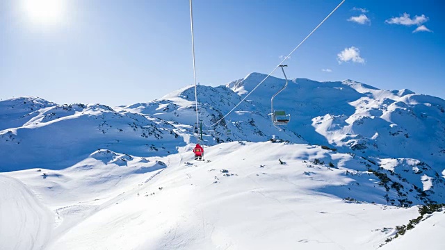 在阳光明媚的冬日里，在山区度假胜地乘坐滑雪缆车视频素材