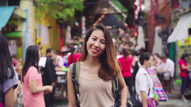 旅行家背包亚洲女人旅行在考山路在曼谷，泰国。快乐的年轻女性在惊人的地标假日旅行，享受她的旅程在传统城市。视频素材