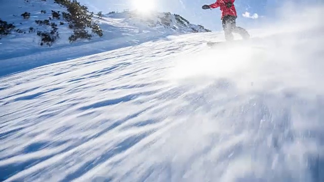 在一个阳光明媚的日子里，滑雪者从滑雪坡上滑下来，雪花向他喷来视频素材