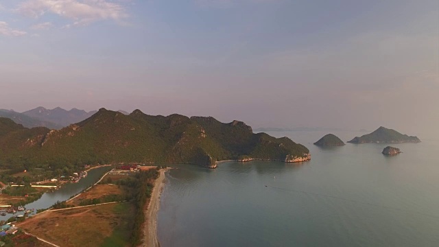 缓慢的航拍降落在泰国岛屿和乡村的Pranburi，而淡粉色和蓝色的天空在日出时柔和地发光视频素材