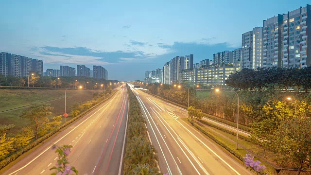 从白天到晚上，新加坡高速公路上的交通被高楼大厦包围视频素材