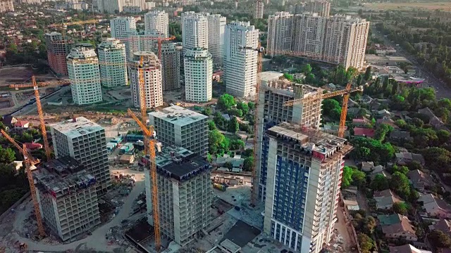 空中无人机拍摄。在大城市的发展中地区建设高层建筑。在图片中，施工起重机和许多房屋正在建设中。镜头向下移动视频素材