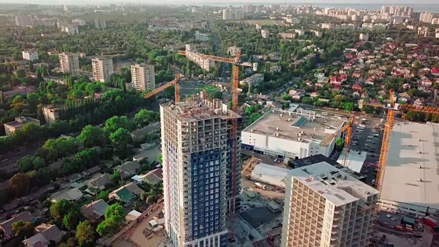 空中无人机拍摄。在大城市的发展中地区建设高层建筑。日落。小型建筑，施工起重机和许多房屋正在建设中。广角镜头视频素材