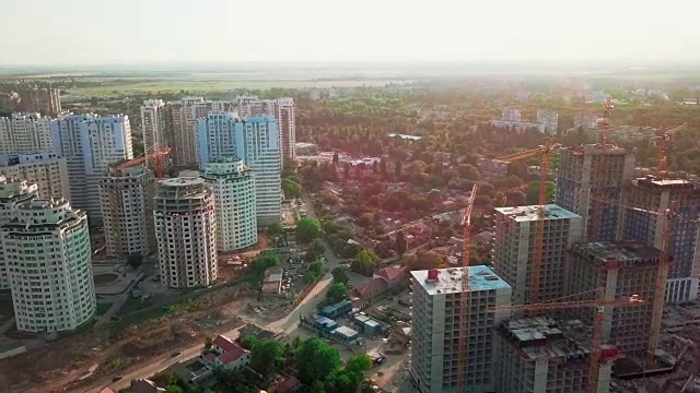 空中无人机拍摄。在大城市的发展中地区建设高层建筑。日落。建筑工地、移交的房屋、施工起重机和许多在建房屋。广角镜头视频素材