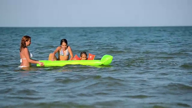 快乐的女人和孩子们在水里冲浪视频素材