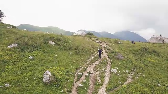 女人走在山间小径，同时徒步旅行的无人机视图视频素材