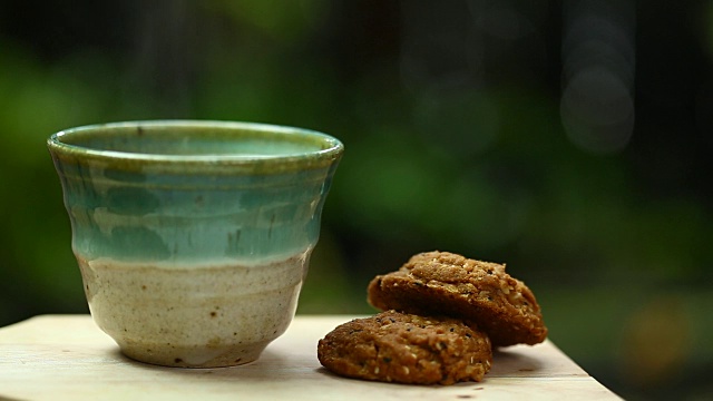 茶杯里的茉莉花绿茶和木桌上的饼干。视频素材