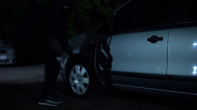 男性罪犯试图在夜间停车时打开汽车，劫车，私人财产视频素材