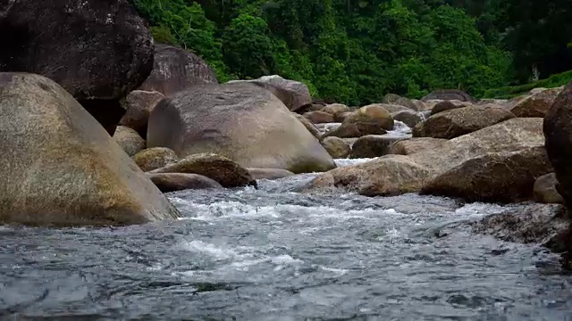 大自然的水从山上通过许多岩石流到河在乡村的小村庄。瀑布落下的声音放松了，平静而祥和。视频素材