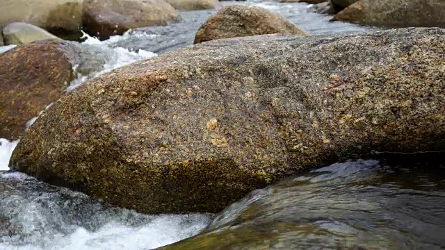 大自然的水从山上通过许多岩石流到河在乡村的小村庄。瀑布落下的声音放松了，平静而祥和。视频素材