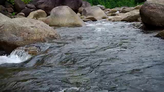 大自然的水从山上通过许多岩石流到河在乡村的小村庄。瀑布落下的声音放松了，平静而祥和。视频素材