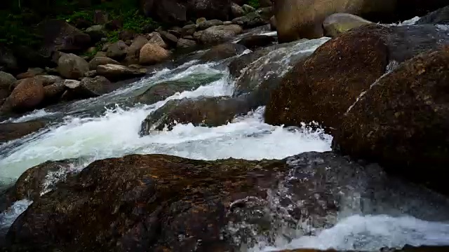 大自然的水从山上通过许多岩石流到河在乡村的小村庄。瀑布落下的声音放松了，平静而祥和。视频素材