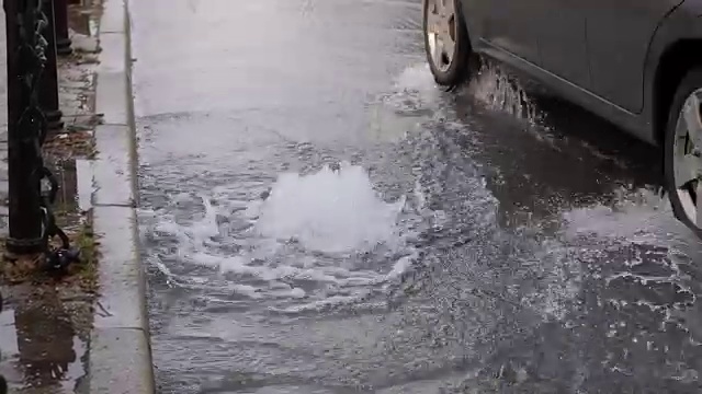 由于地下水管破裂，水从道路排水系统流出，汽车经过视频素材