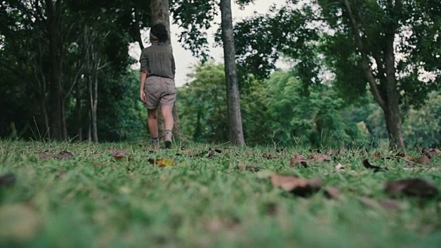 在森林里穿过草丛的年轻女子。视频素材