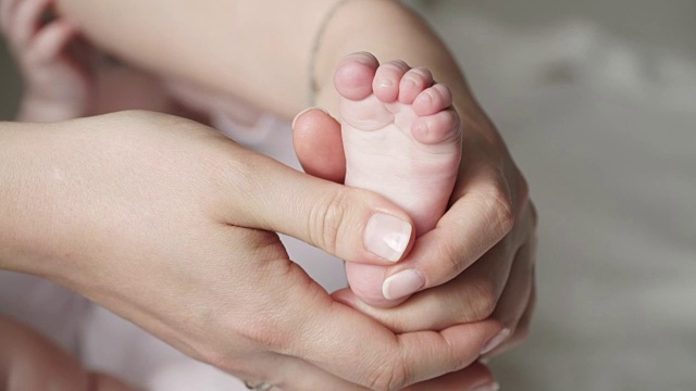 母亲的手抚摸着新生婴儿的脚视频素材