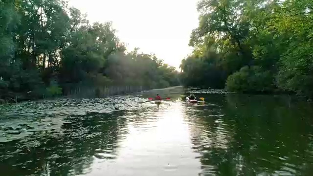 两条皮划艇沿着一条风景优美的河流航行。鸟瞰图。视频素材