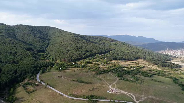 航拍与缓慢移动松树森林旁边的小山镇房子视频素材