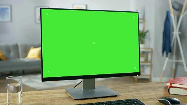 现代个人电脑模型绿色屏幕显示站在舒适的家庭办公室的书桌上。室内设计师创造的客厅，有品位，有风格。视频素材