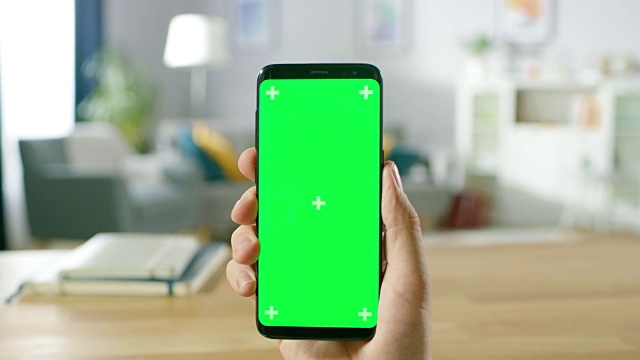 一个男人的特写握住和在现代绿色模拟屏幕智能手机上做手势。用手指触摸手机色度键屏幕。视频素材