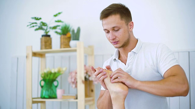 肖像男按摩师按摩美丽的年轻女子腿脚在水疗沙龙的桌子上。视频素材