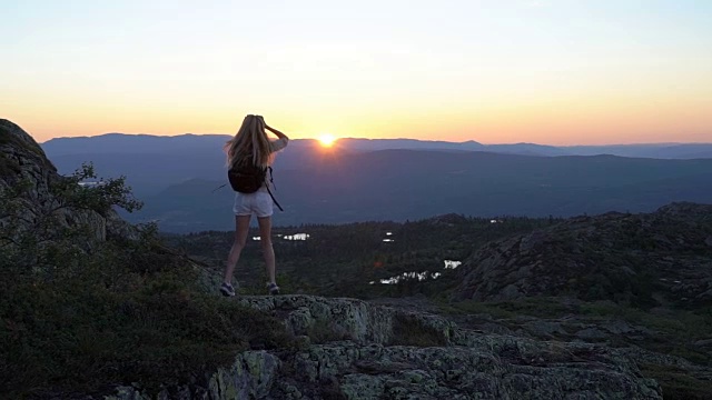 幸福的年轻女子在日落高山峻岭张开双手挥手视频素材