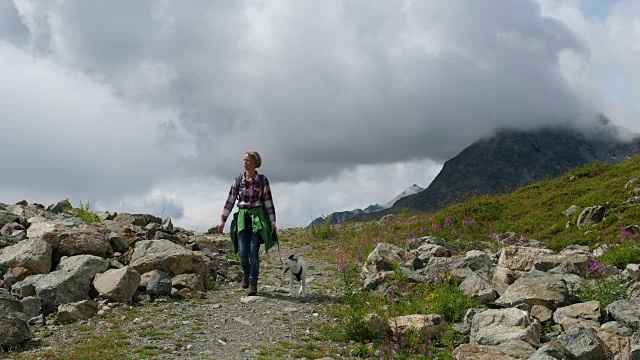 在瑞士恩加丁，一名妇女带着狗徒步旅行视频素材