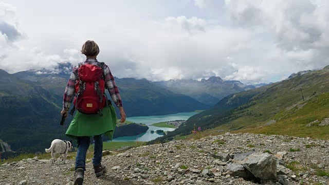 在瑞士恩加丁，一名妇女带着狗徒步旅行视频素材