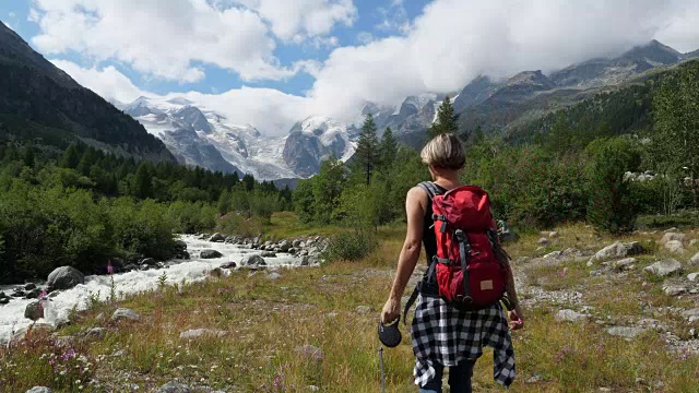 在瑞士恩加丁，一名妇女带着狗徒步旅行视频素材