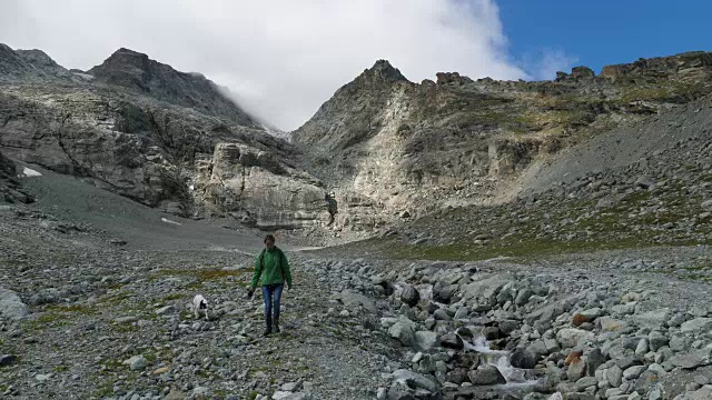 在瑞士恩加丁，一名妇女带着狗在Corvatsch徒步旅行视频下载