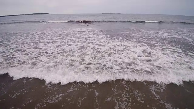 美丽的4K海滩空中鸟瞰海浪撞击一个空的海滩从上面海浪冲刷光滑的沙滩视频素材