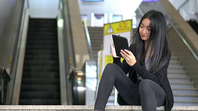 女孩在电梯前玩平板电脑视频素材