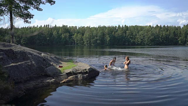 一家人在芬兰的一个森林湖里游泳视频素材