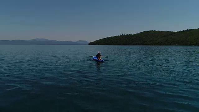 一个孤独的女人在湖上或海上划皮艇。一个快乐的成熟女人在一个夏天的湖中或海里划独木舟。视频素材