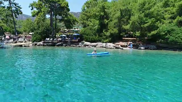 一个孤独的女人在湖上或海上划皮艇。一个快乐的成熟女人在一个夏天的湖中或海里划独木舟。视频素材