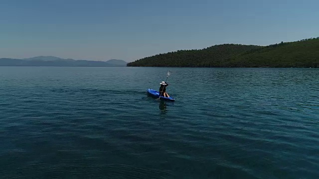 一个孤独的女人在湖上或海上划皮艇。一个快乐的成熟女人在一个夏天的湖中或海里划独木舟。视频素材