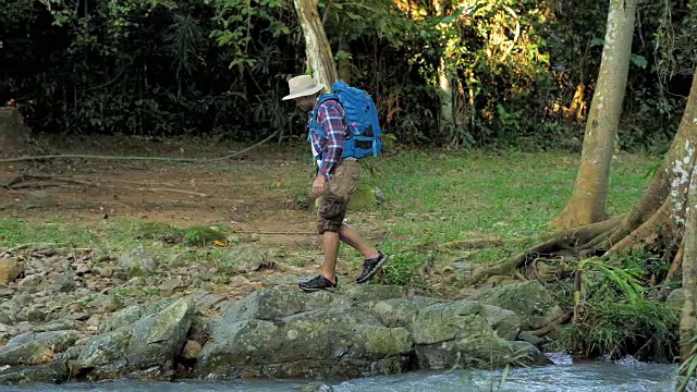 冒险家亚洲男性。在森林里的石头上行走跳跃。冒险和极限旅游，克服障碍。旅行的生活方式和成功的概念。视频慢动作视频素材