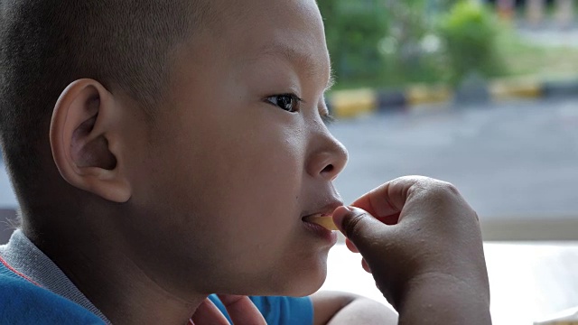 近距离观察小亚洲男孩喜欢吃薯条。视频慢动作视频素材