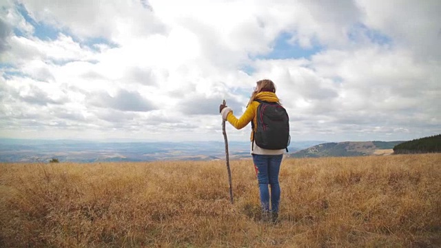 在空旷的山地草地上徒步旅行的女人。视频素材