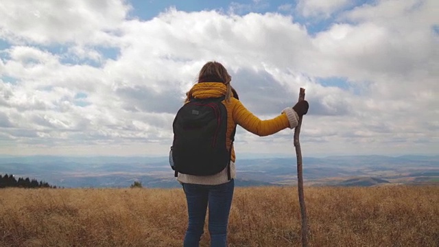 在空旷的山地草地上徒步旅行的女人。视频素材