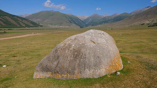 在高地景观的绿色草地上的巨石和蓝天上的山峰视频素材