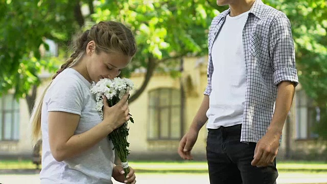 小伙子着急，跑到漂亮姑娘跟前送花束，初恋视频素材