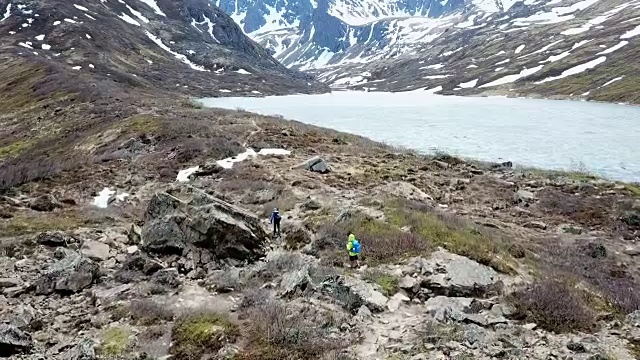 鸟瞰图两个徒步旅行者在岩石湖畔徒步旅行视频素材